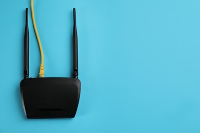 Photo of Modern Wi-Fi router on light blue background, top view. Space for text