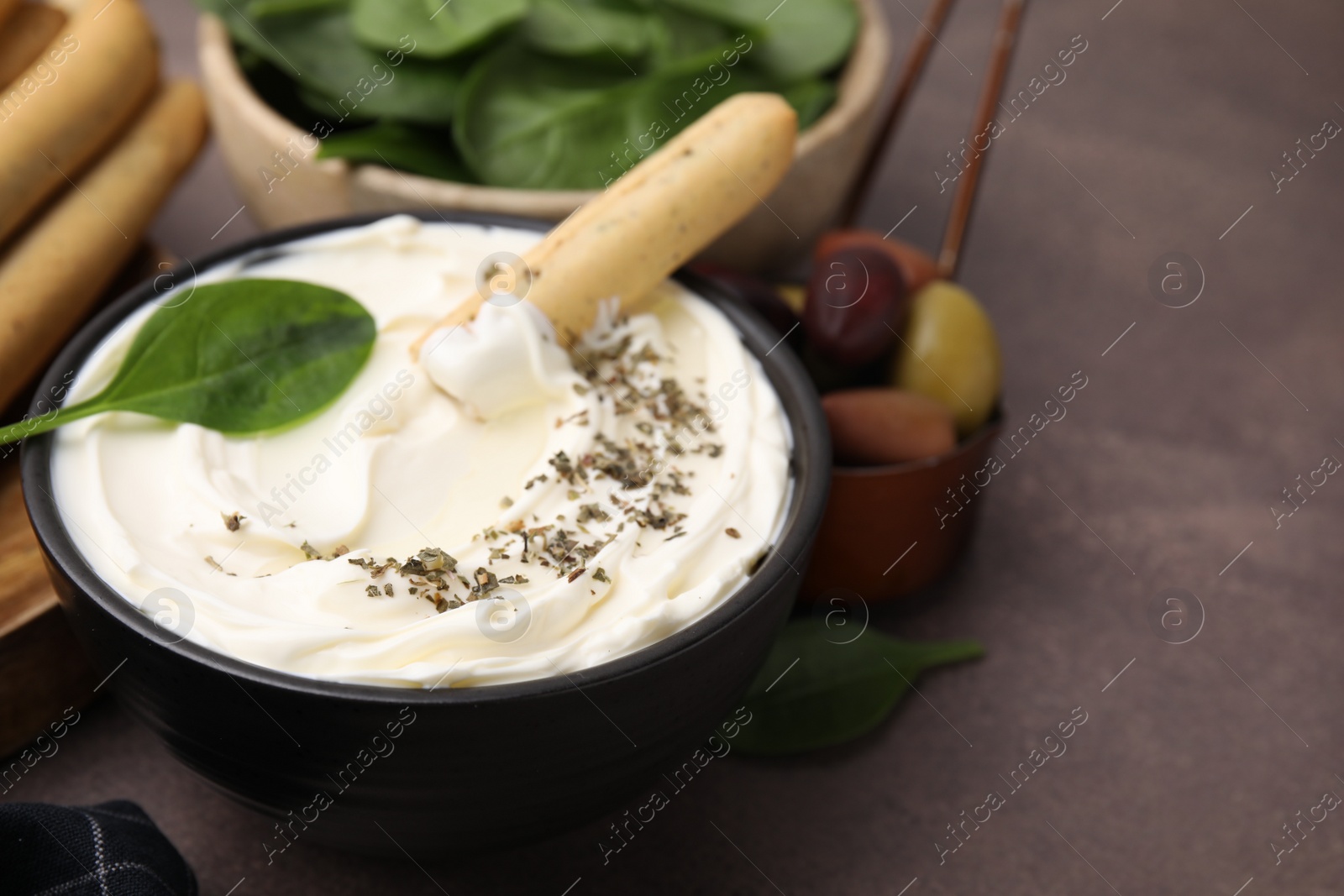 Photo of Delicious cream cheese with grissini stick and spices on grey table, closeup