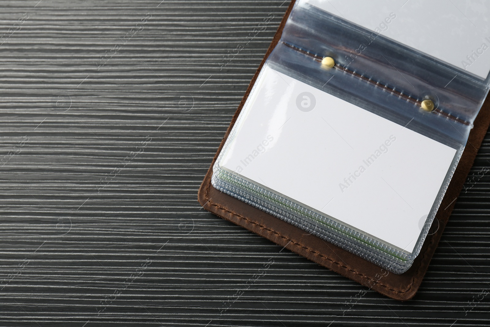 Photo of Leather business card holder with blank cards on grey table, top view. Space for text