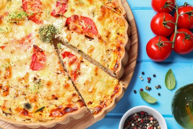 Photo of Tasty quiche with tomatoes, microgreens and cheese served on light blue wooden table, flat lay