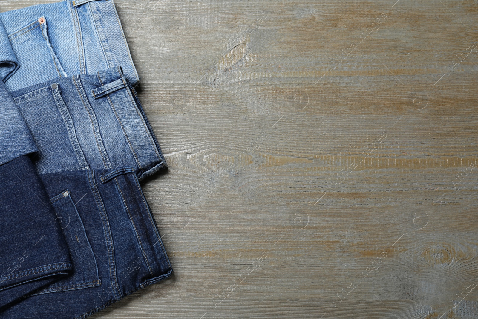Photo of New stylish jeans on wooden background, flat lay. Space for text
