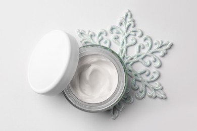 Photo of Winter skin care. Hand cream and decorative snowflake on white background, top view