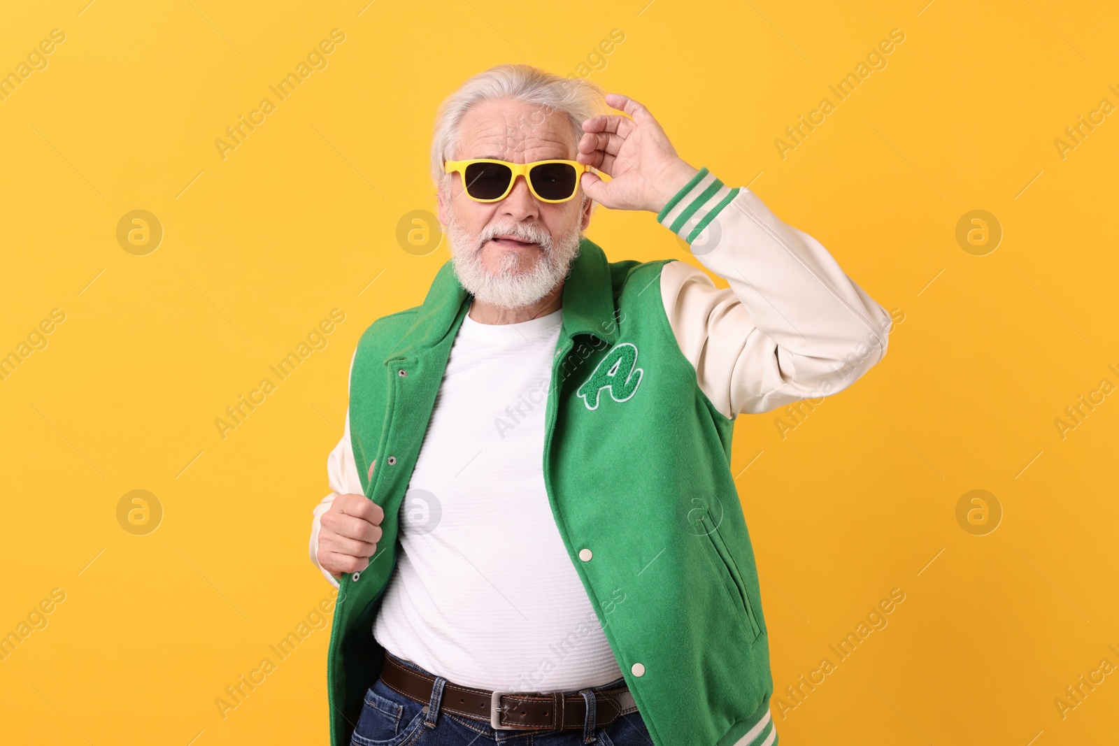 Photo of Portrait of grandpa with stylish sunglasses on yellow background