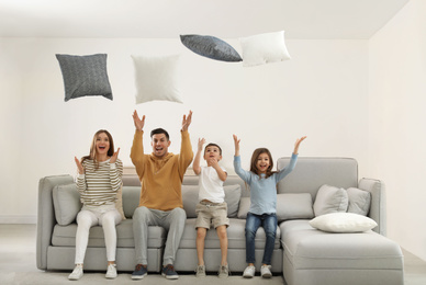 Happy family playing with pillows in living room