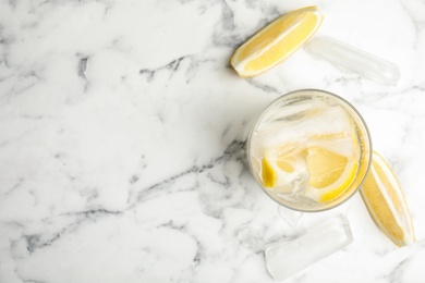 Soda water with lemon slices and ice cubes on white marble table, flat lay. Space for text