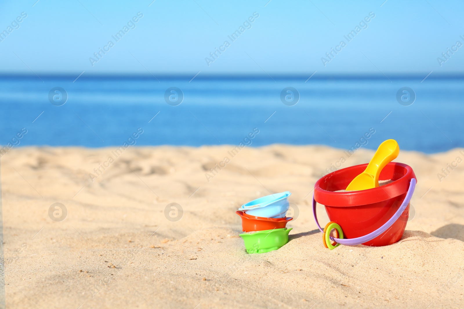 Photo of Set of plastic beach toys on sand near sea. Space for text