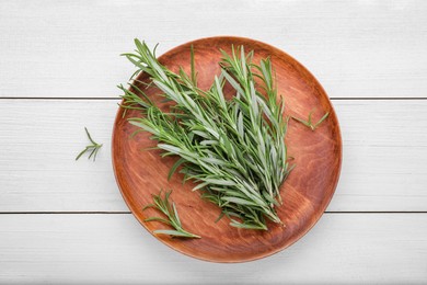 Photo of Plate with fresh green rosemary sprigs on white wooden table, top view