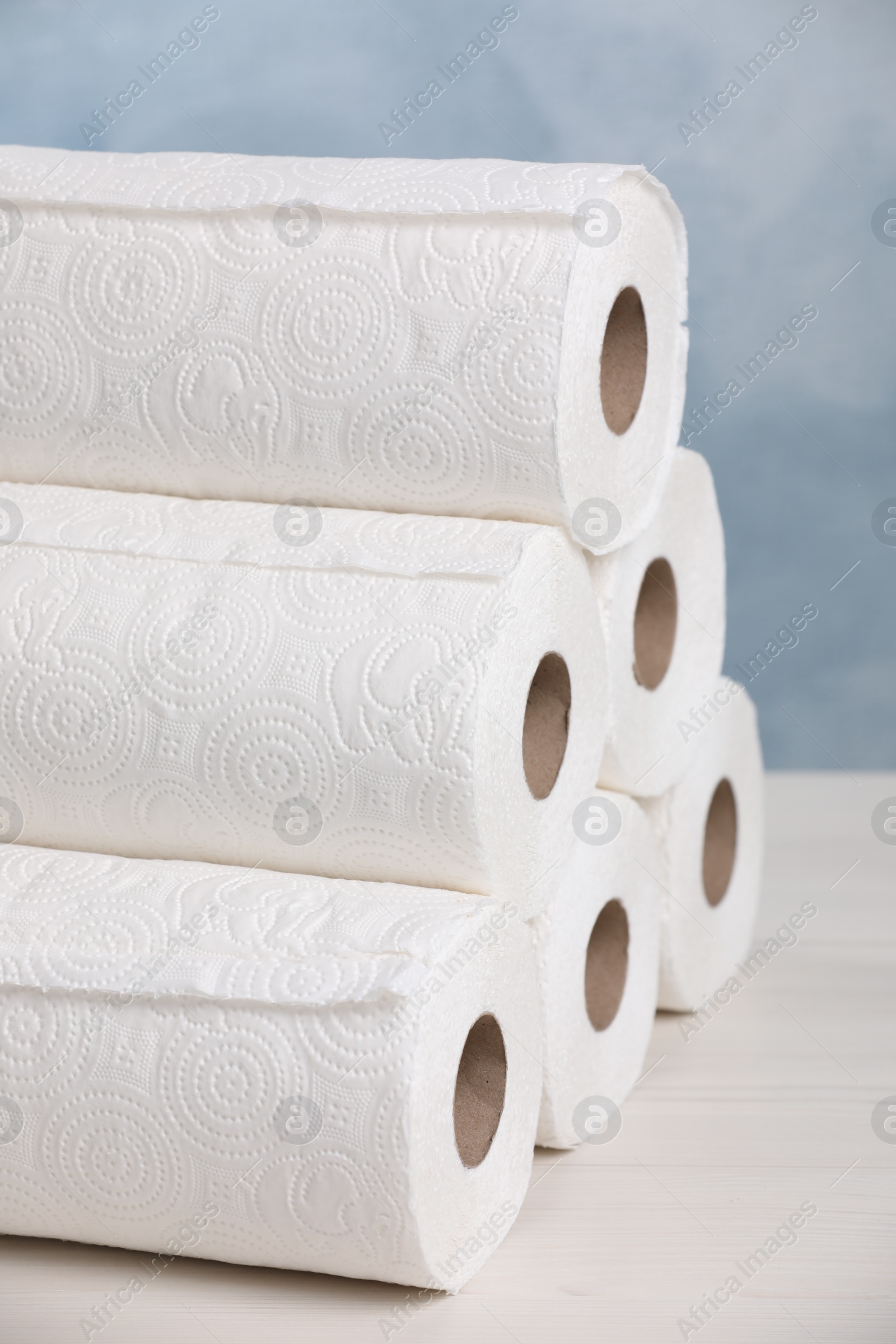 Photo of Many rolls of paper towels on white wooden table