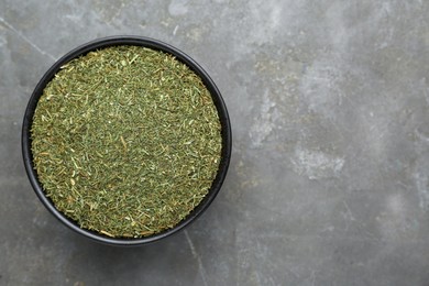 Photo of Bowl with dried dill on grey table, top view. Space for text