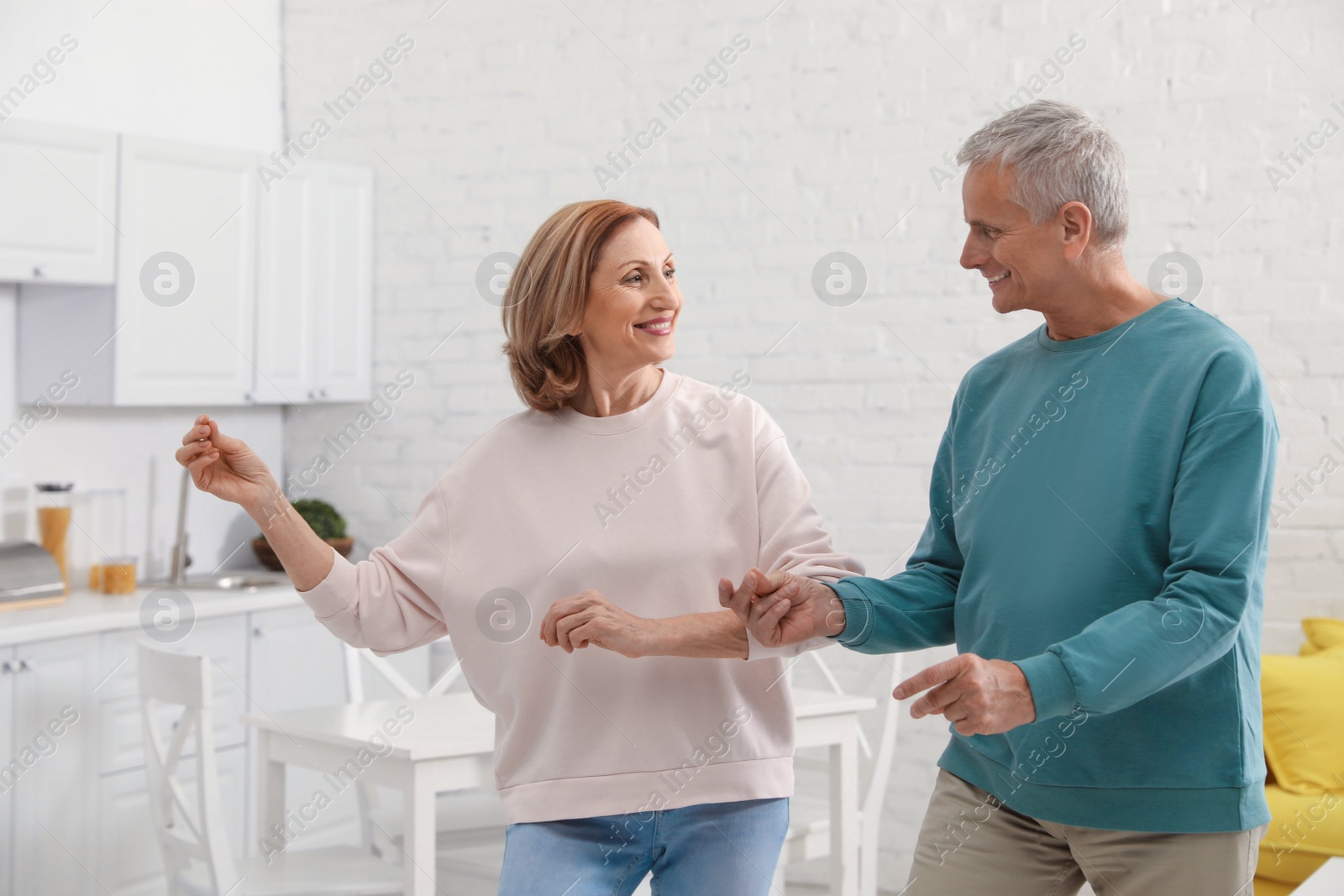 Photo of Happy senior couple dancing together in kitchen