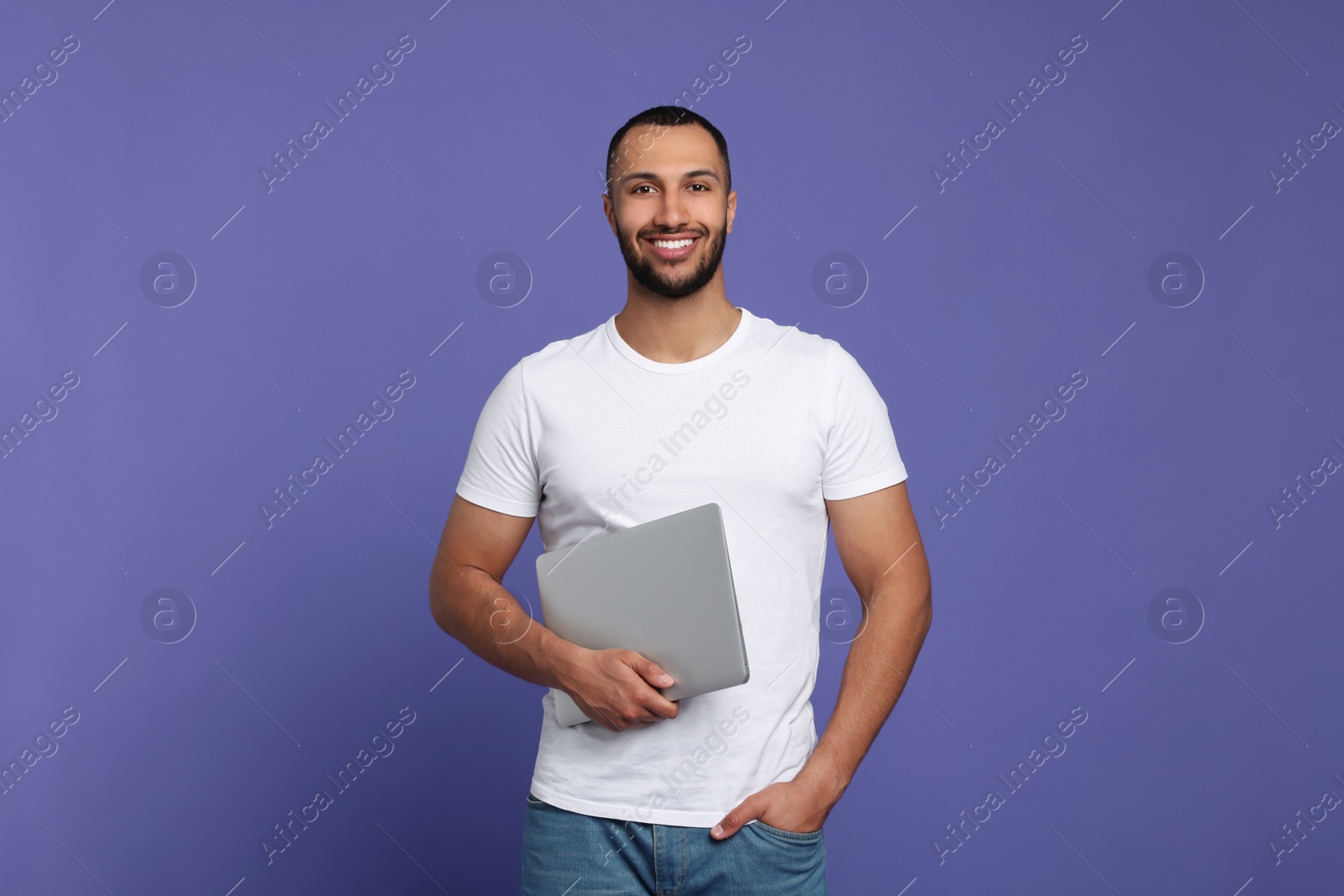 Photo of Smiling young man with laptop on lilac background