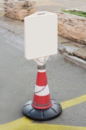 Photo of Traffic cone with blank sign on asphalt outdoors