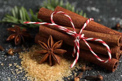 Photo of Different aromatic spices on grey textured table, closeup