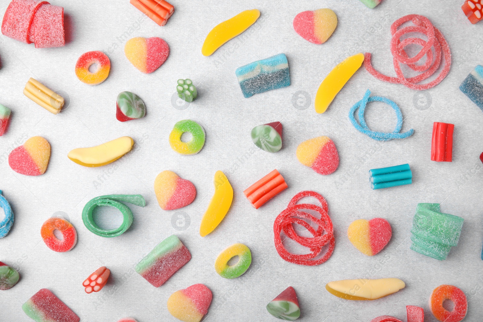 Photo of Many tasty colorful jelly candies on white table, flat lay