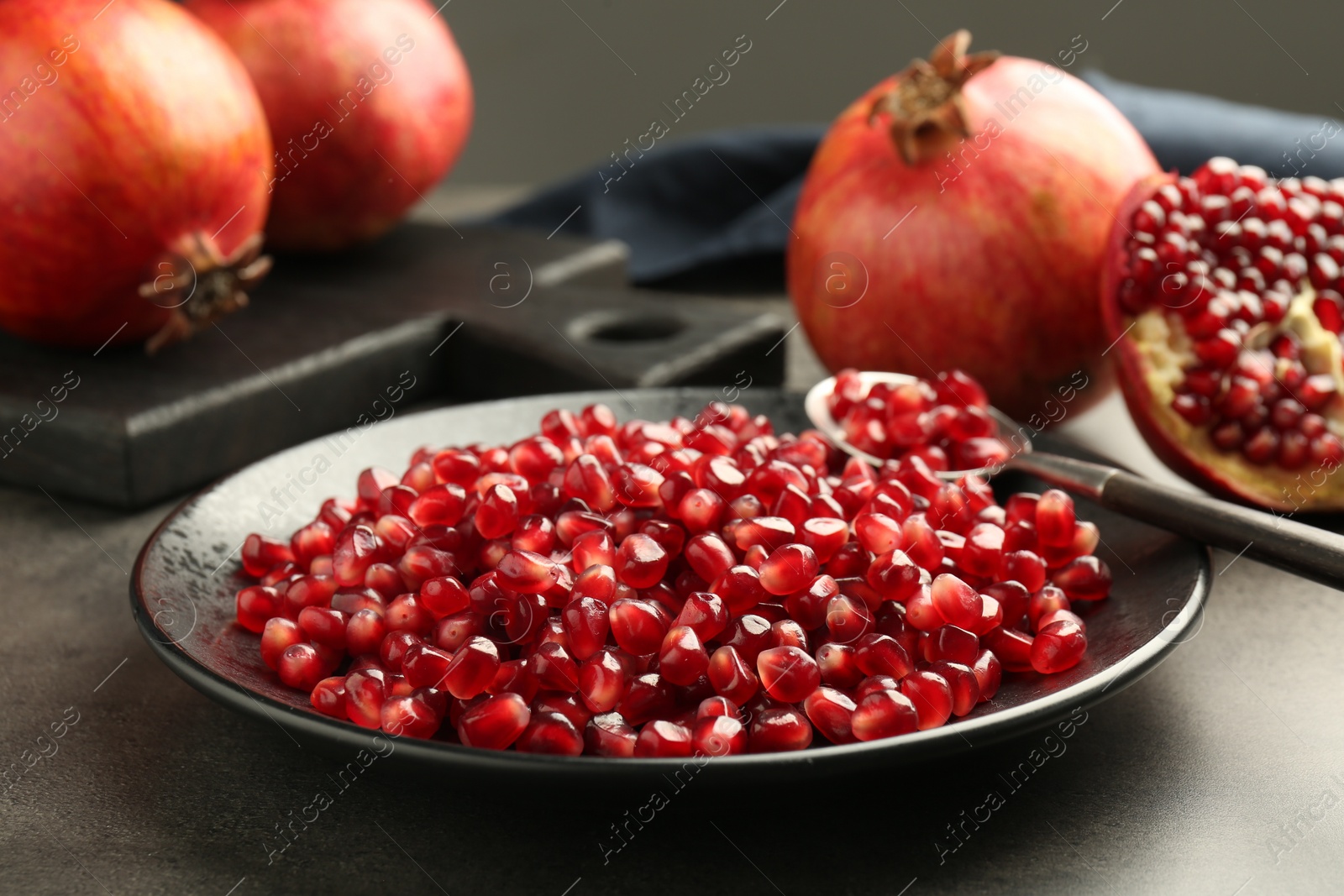 Photo of Ripe juicy pomegranate grains on grey table