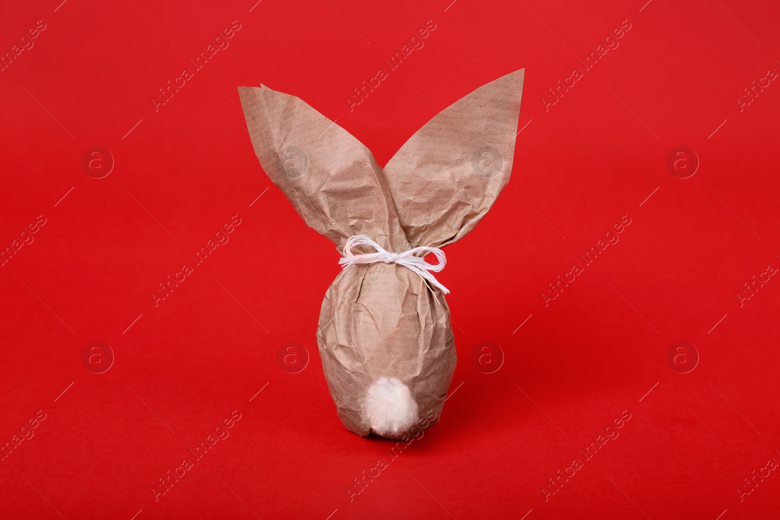 Photo of Easter bunny made of kraft paper and egg on red background