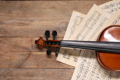 Photo of Violin and music sheets on wooden table, top view. Space for text