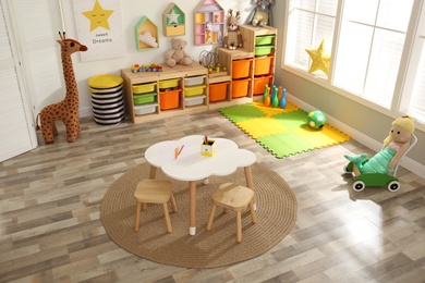 Photo of Stylish playroom interior with modern furniture and soft toys, above view