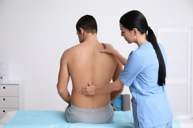 Photo of Orthopedist examining man's back in clinic. Scoliosis treatment