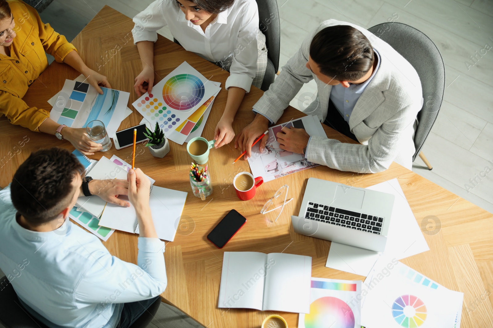 Photo of Team of professional designers working together at table in office