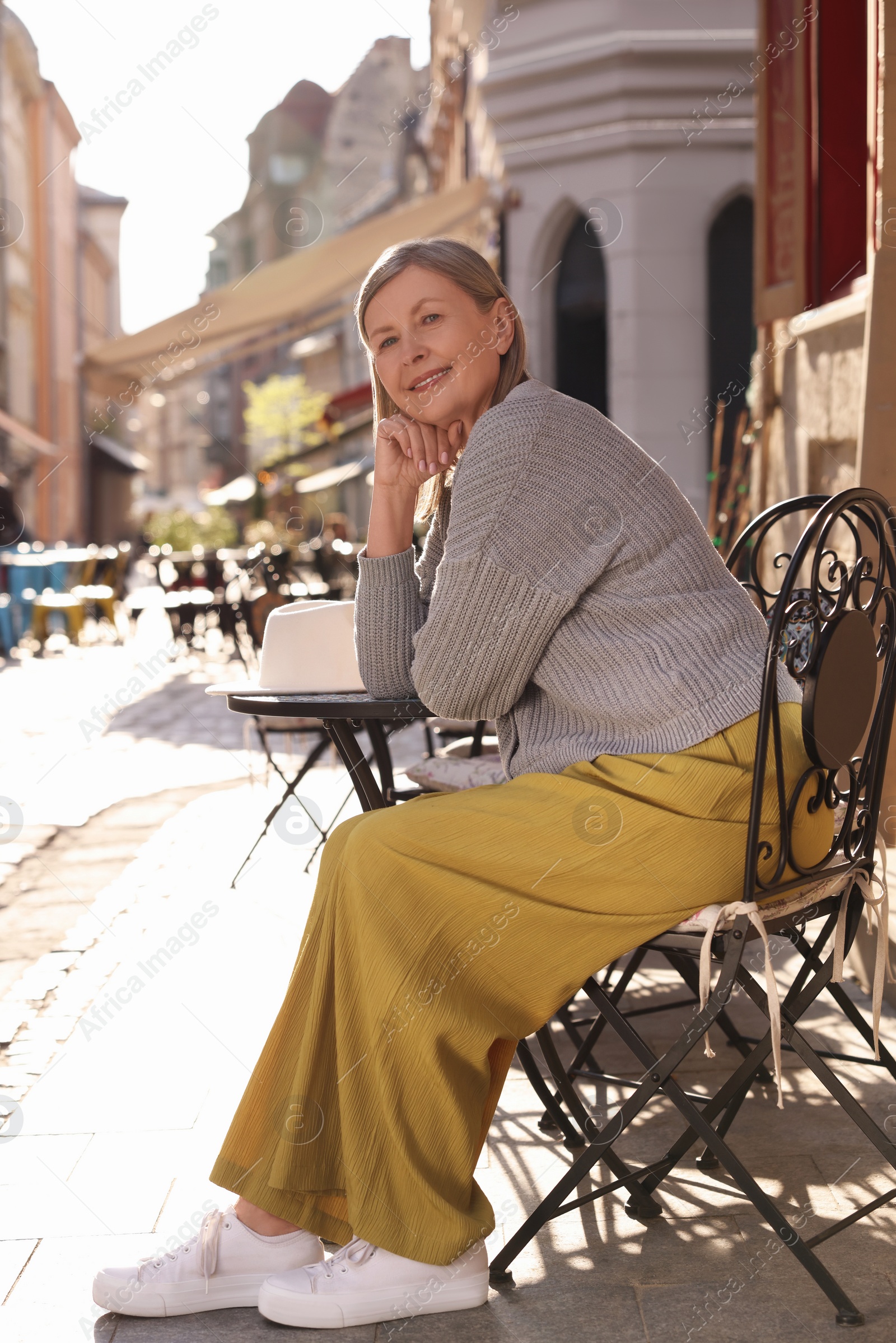 Photo of Beautiful senior woman sitting in outdoor cafe, space for text