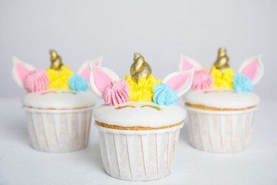 Cute sweet unicorn cupcakes on white table