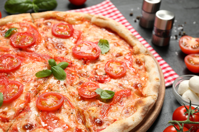 Photo of Delicious pizza Margherita and ingredients on dark grey table, closeup