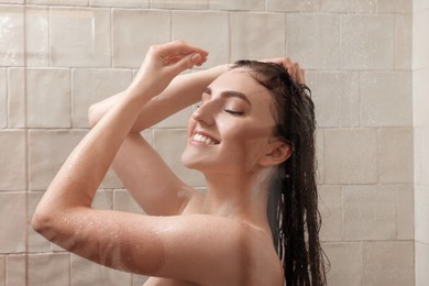 Photo of Happy woman washing hair while taking shower at home