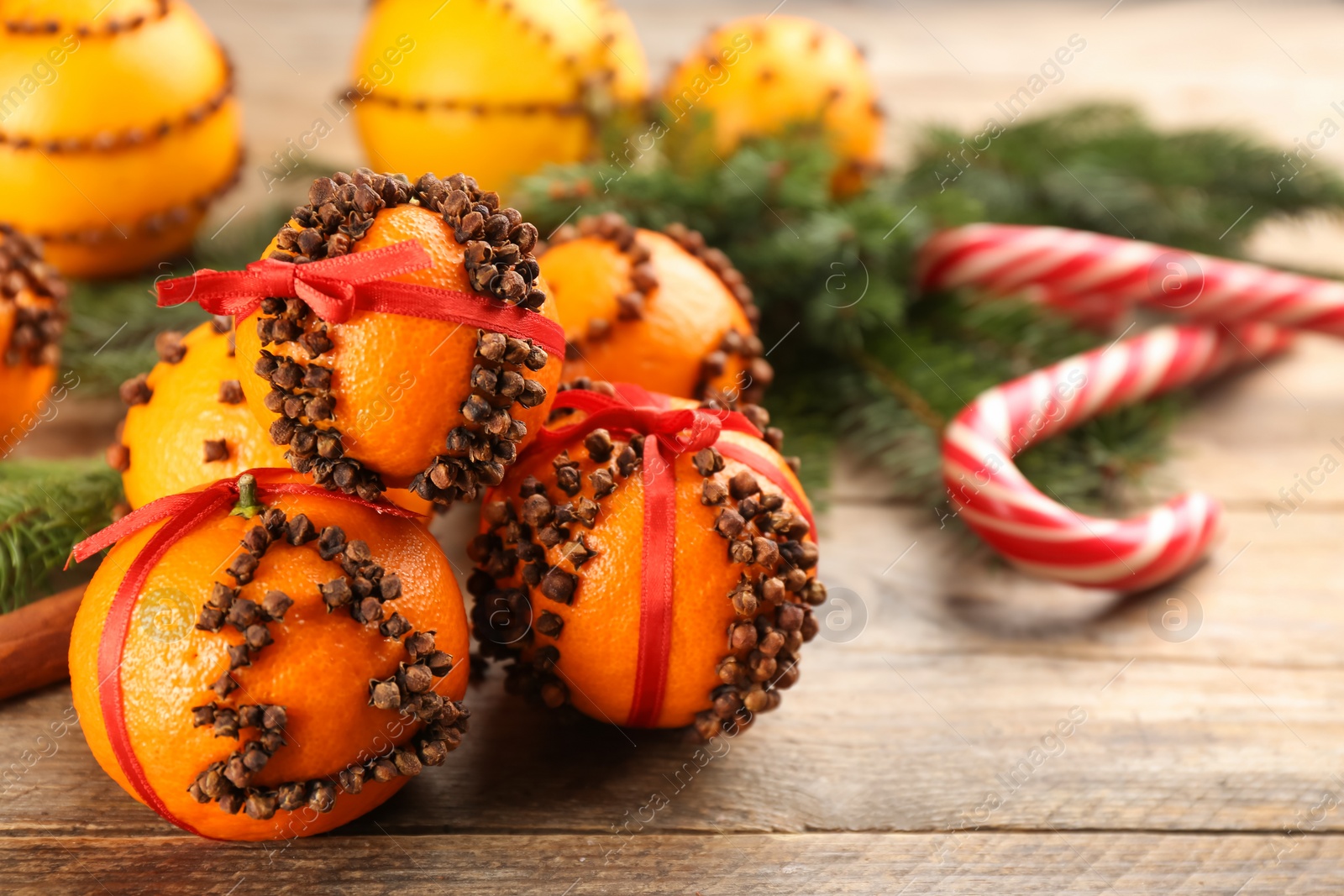 Photo of Pomander balls made of fresh tangerines with cloves  on wooden table. Space for text