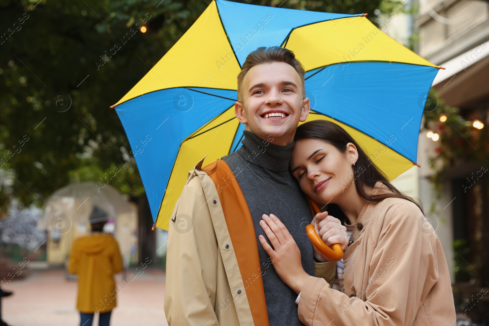 Photo of Lovely young couple with umbrella walking under rain on city street