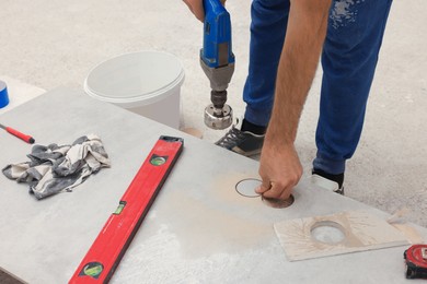 Worker making socket hole in tile indoors, closeup