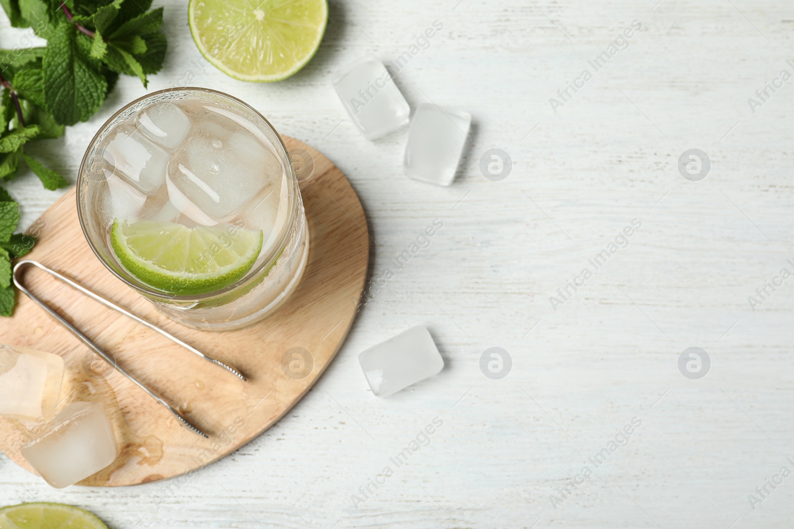 Photo of Flat lay composition of cocktail with vodka, ice and lime on white wooden table. Space for text