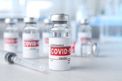 Photo of Glass vials with COVID-19 vaccine and syringe on light table