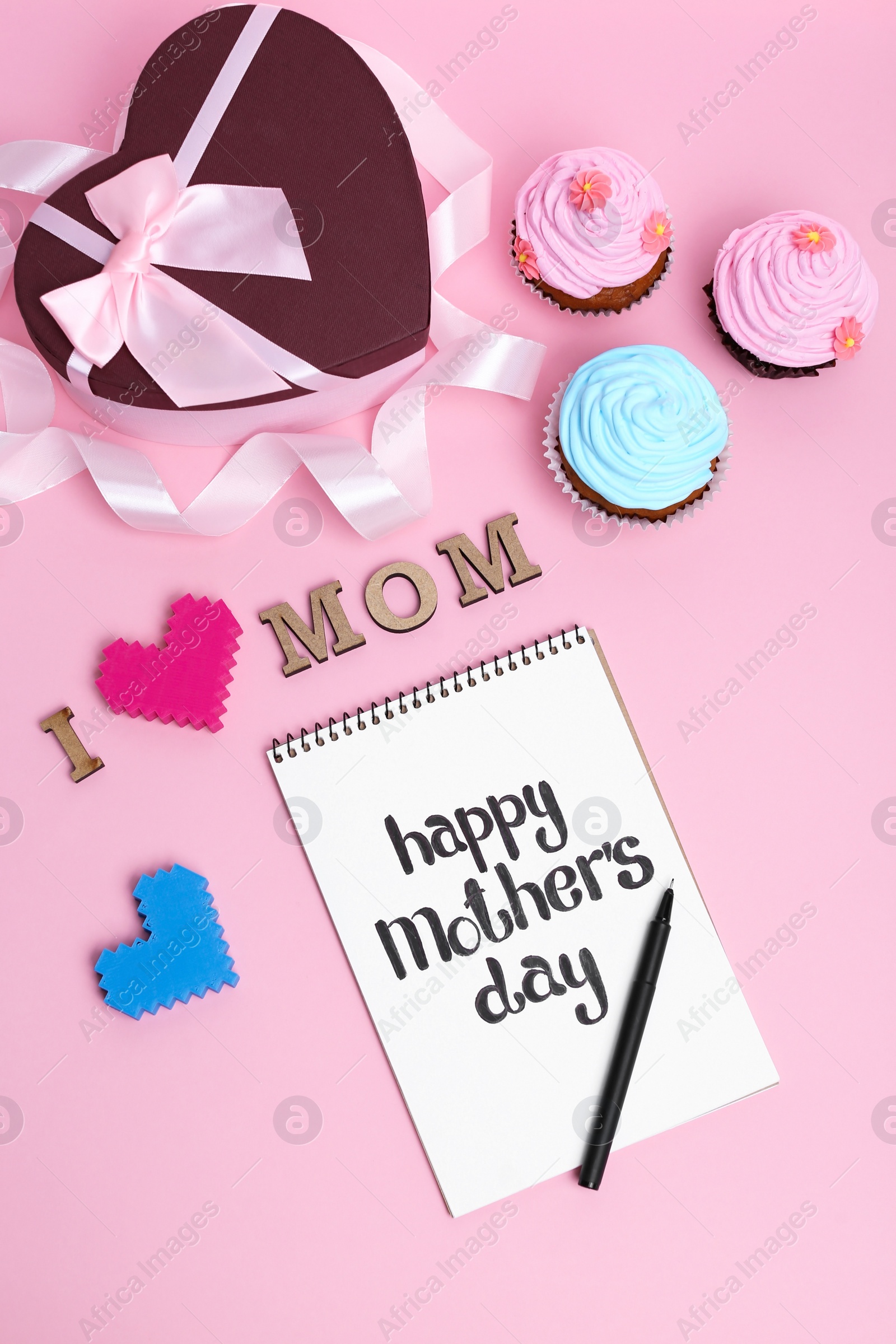 Photo of Flat lay composition with cupcakes, gift box and notebook for Mother's Day on color background