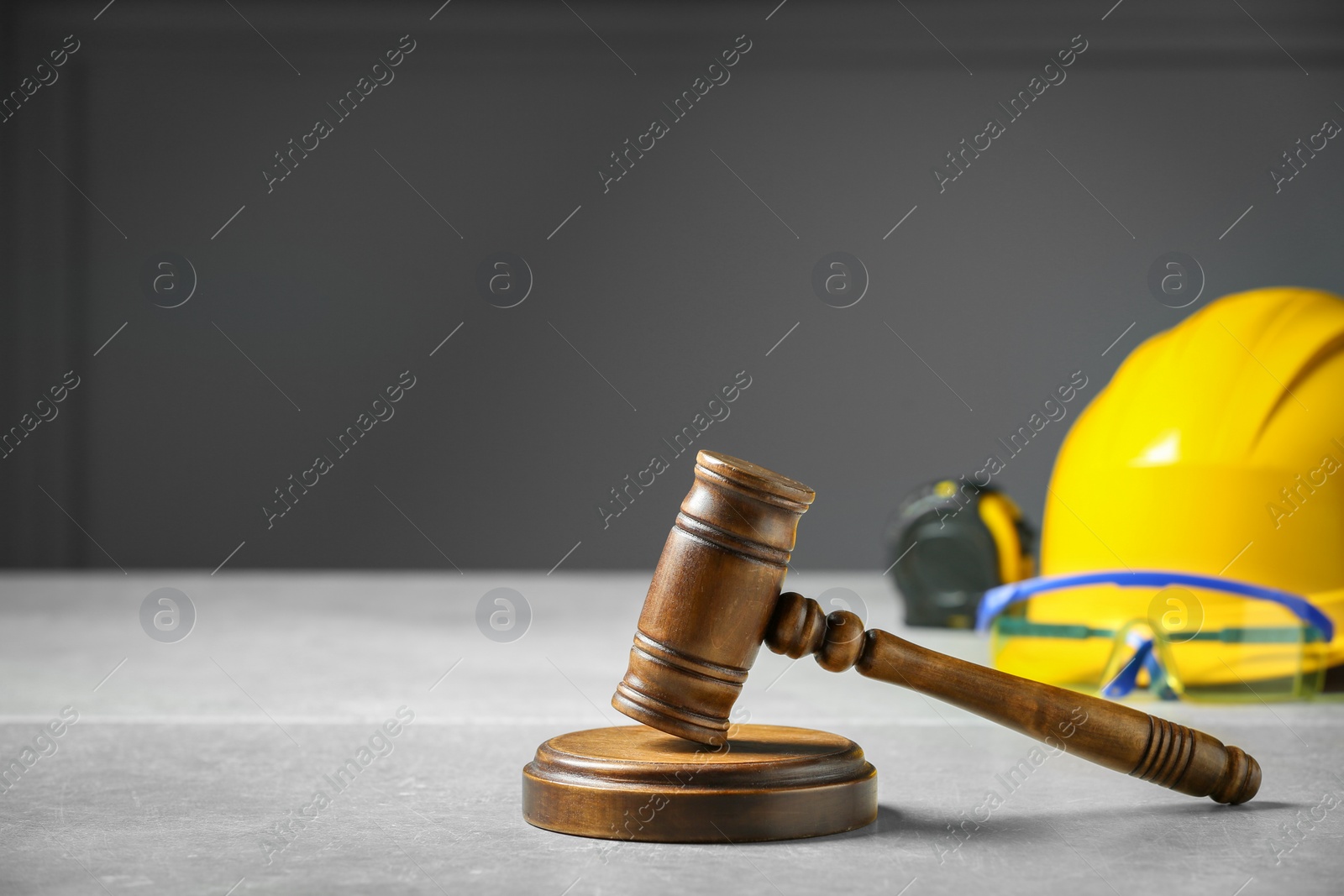 Photo of Construction and land law concepts. Judge gavel, tape measure with hardhat on light grey table, space for text