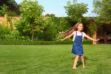 Photo of Cute little girl running in green park on summer day