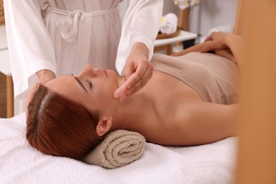 Photo of Young woman receiving facial massage with rose quartz gua sha tool in beauty salon, closeup