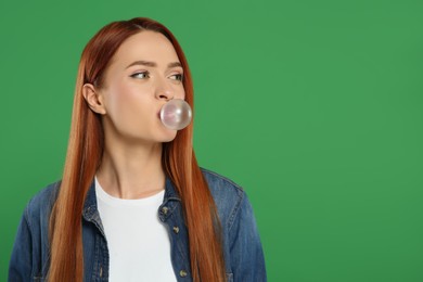 Photo of Beautiful woman blowing bubble gum on green background, space for text