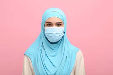 Portrait of Muslim woman in hijab and medical mask on pink background