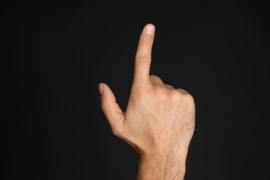 Man pointing at something on black background, closeup. Finger gesture