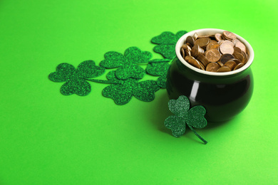 Photo of Pot of gold coins and clover leaves on green background, space for text. St. Patrick's Day celebration