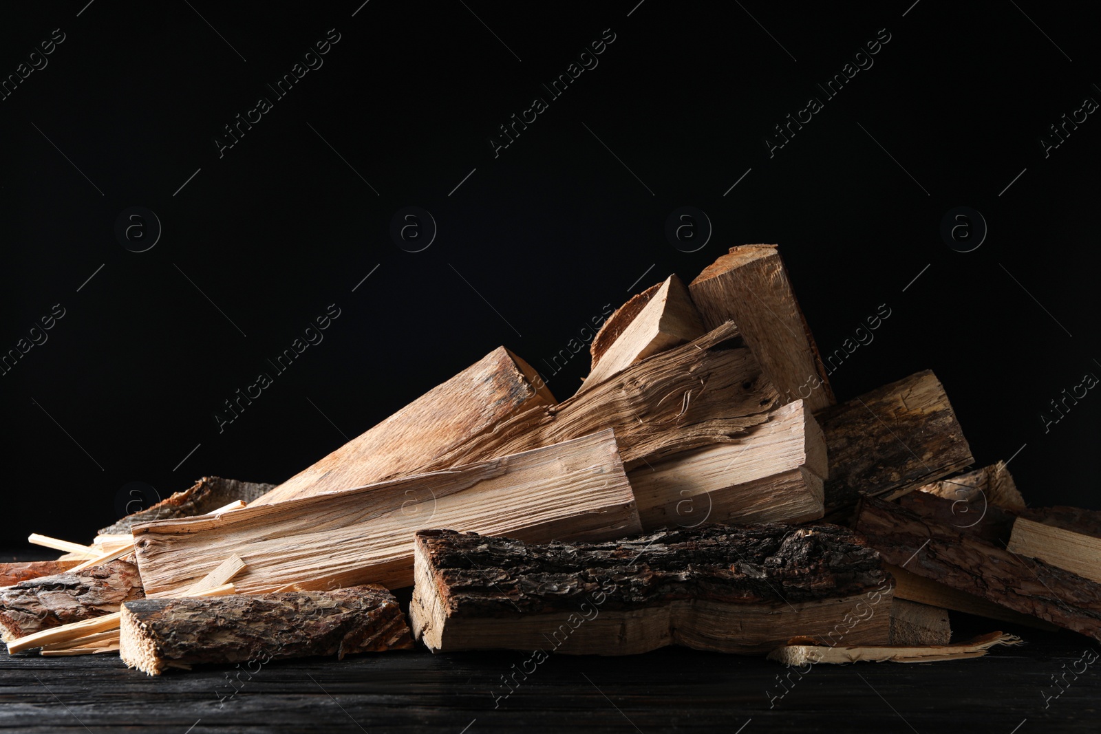 Photo of Cut firewood on table against black background