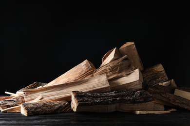 Photo of Cut firewood on table against black background