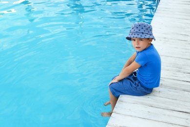 Photo of Little child near outdoor swimming pool. Dangerous situation