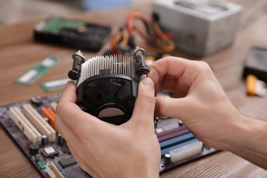 Male technician repairing computer fan at table, closeup