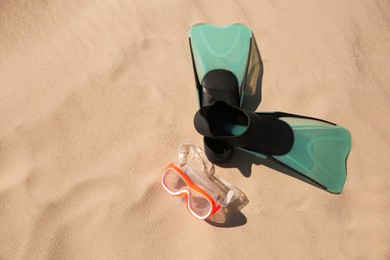 Photo of Pair of flippers and diving mask on sandy beach, flat lay. Space for text