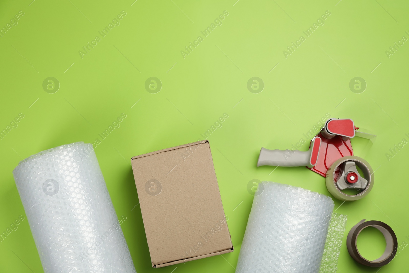 Photo of Flat lay composition with bubble wrap rolls on green background, space for text