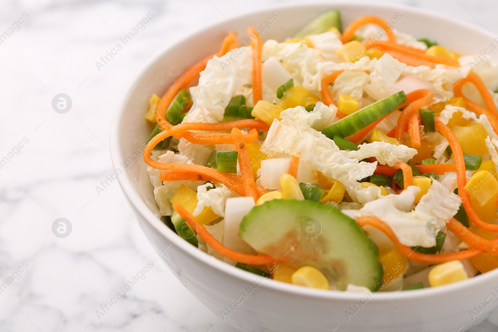 Photo of Tasty salad with Chinese cabbage, carrot, corn and cucumber in bowl on white marble table, closeup