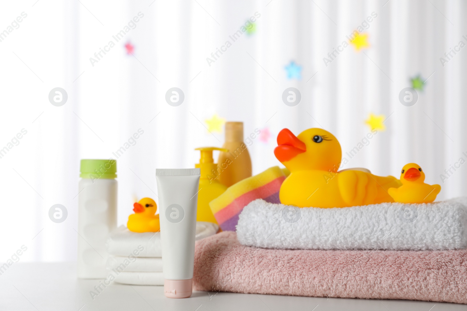 Photo of Towels, rubber ducks and baby care products on white table indoors