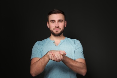 Photo of Man showing BELIEVE gesture in sign language on black background